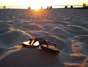 Flip Flops am Strand, die von der Sonne angeschienen werden